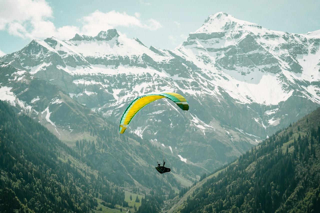 A paraglider is flying over a mountain range, Ultra