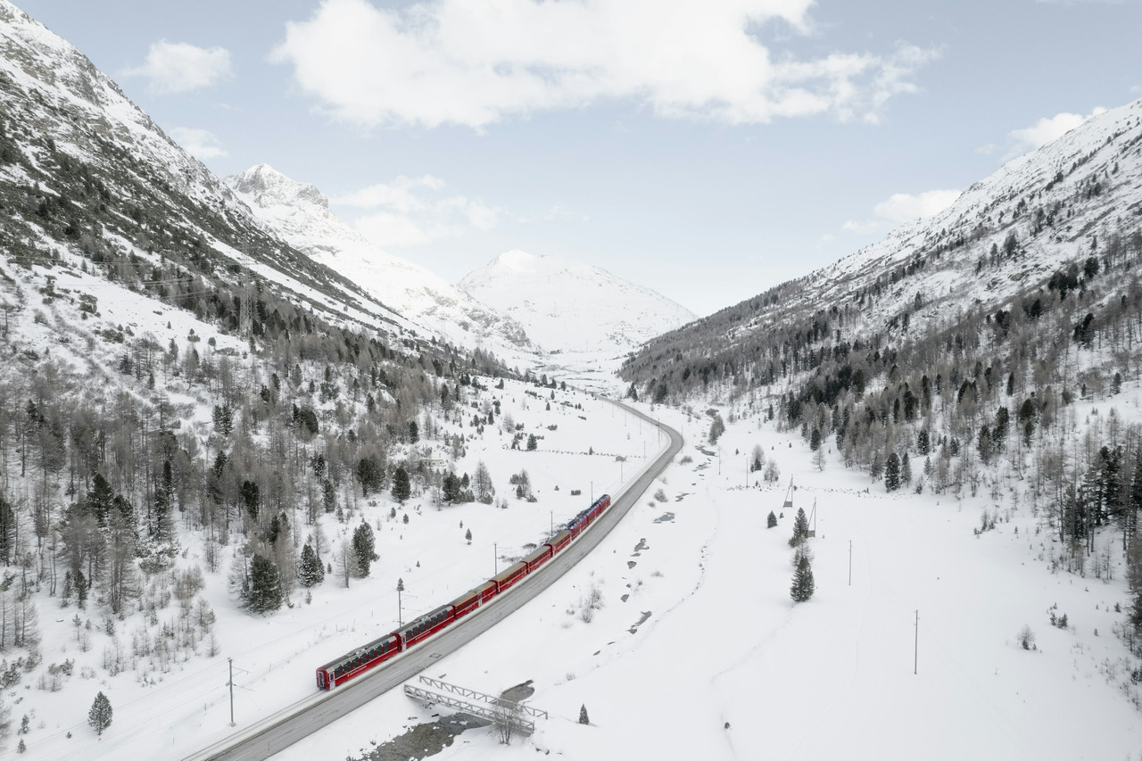 a red train traveling through a snow covered mountain, Ultra