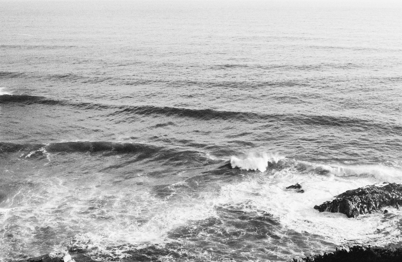 Black and white ocean waves crashing against a rocky shore, Ultra