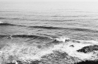 Black and white ocean waves crashing against a rocky shore, Ultra