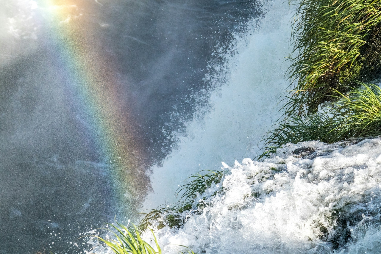 Rainbow over a powerful waterfall with green foliage, Ultra