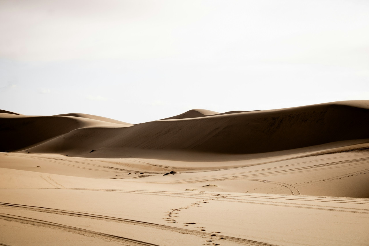 Sand dunes stretch into the distance under a pale sky, Ultra
