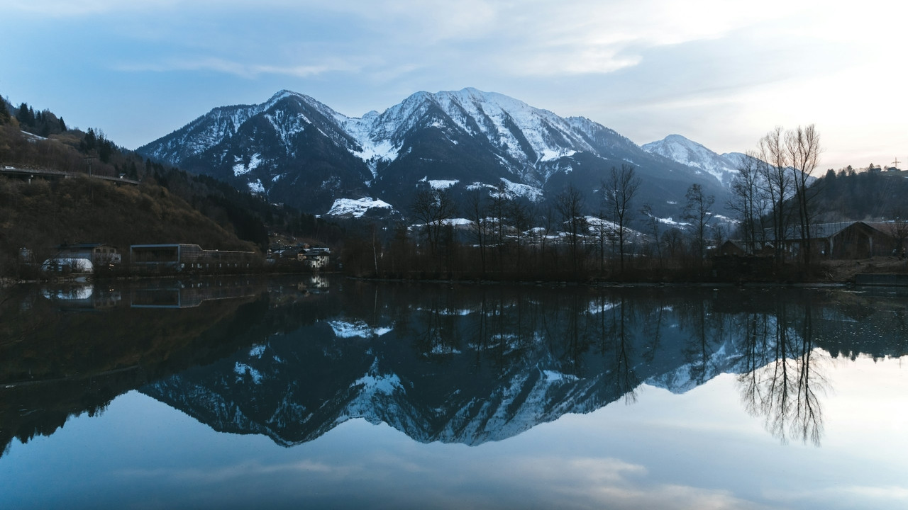 Snow-capped mountains reflected in the calm water of a lake at low light, Ultra